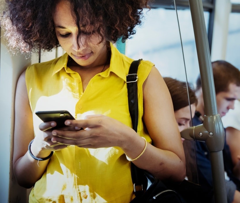A woman looks down at her phone in order to install a general software update while riding the bus.