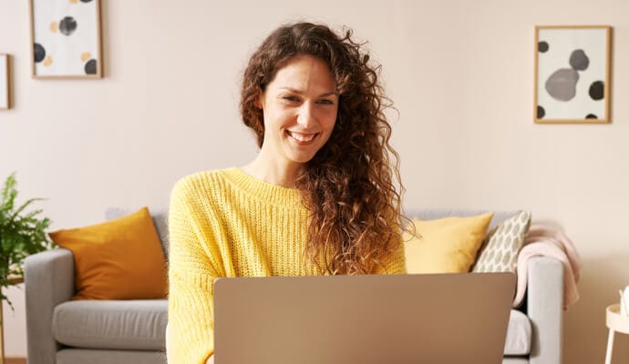Lady smiling using laptop launching Norton Safe Search.