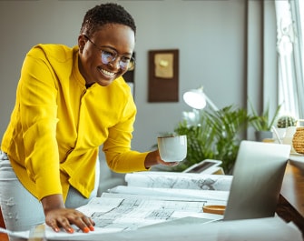 Smiling woman holding a cup looking at a laptop